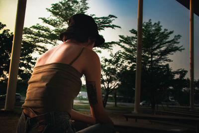 Rear view of woman sitting against trees