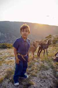 Boy a child of four years 4 walks with goats on a mountain in dagestan during sunset