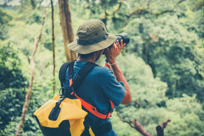 Rear view of man holding hat in forest