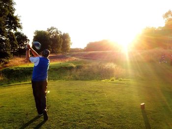 Golfer hitting ball on golf course during sunny day