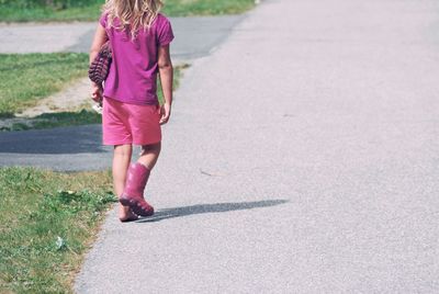 Rear view of girl walking on road