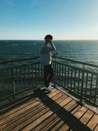 Full length of man standing on railing against sea