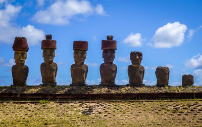 Statues on stone wall against sky