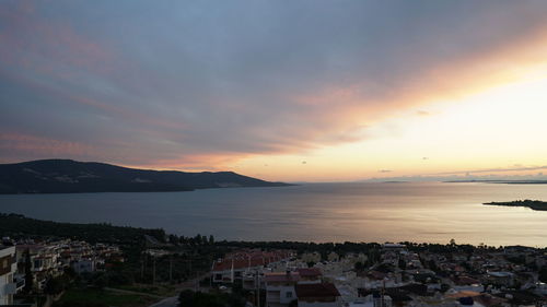 Scenic view of sea by town against sky during sunset