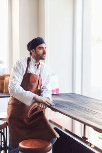 Thoughtful male owner standing by table in grocery store