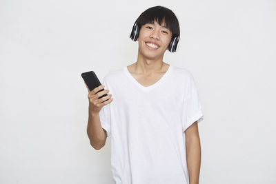 Mid adult man using smart phone against white background