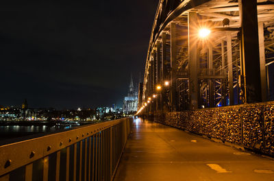 Illuminated city street against sky at night