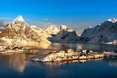 Scenic view of lake by snowcapped mountains against sky