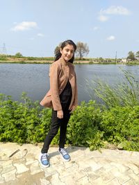 Portrait of teenage girl standing against lake