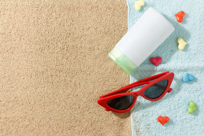 High angle view of eyeglasses by bottle at beach