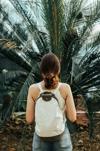 Rear view of woman standing by palm tree