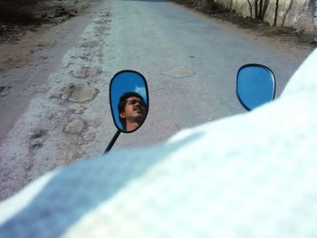 Reflection of man on side-view mirror of motorcycle