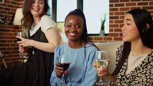 Portrait of smiling friends toasting drinks on table