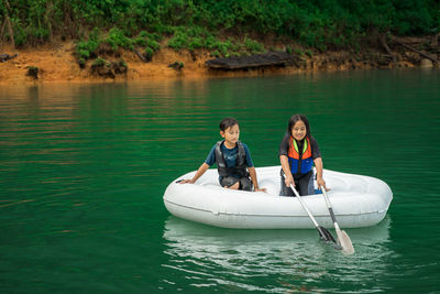 Children wearing life jackets paddling on an inflatable boat in kenyir lake, malaysia.
