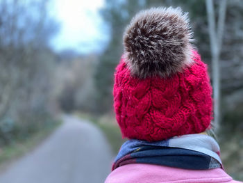 Rear view of woman wearing a knit hat walking in woodlands