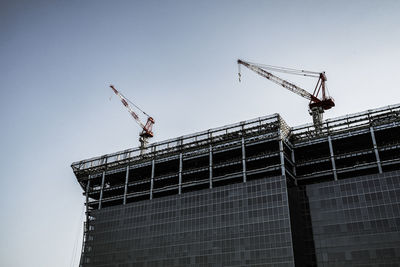 Low angle view of crane at construction site against sky