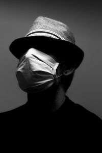 Close-up of man wearing hat against gray background