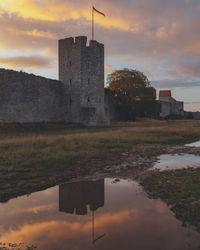 Reflection of old building in lake against sky during sunset