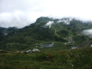 Scenic view of green mountains against cloudy sky