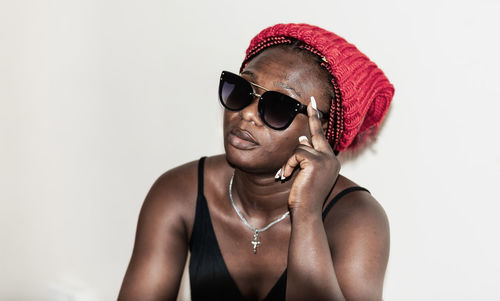 Portrait of young man wearing sunglasses standing against white background