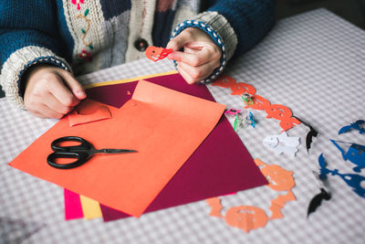 Midsection of woman making paper pumpkins for halloween