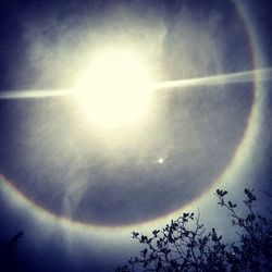 Low angle view of sun shining through clouds