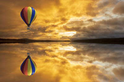 Hot air balloon flying over sea against sky during sunset