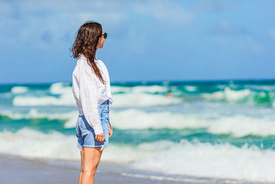 Rear view of young woman standing at beach