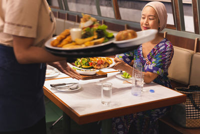 Happy woman customer with smile while getting food from waitress in restaurant