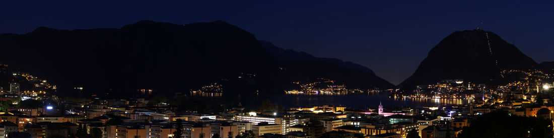 Sailboats in city by sea against sky at night