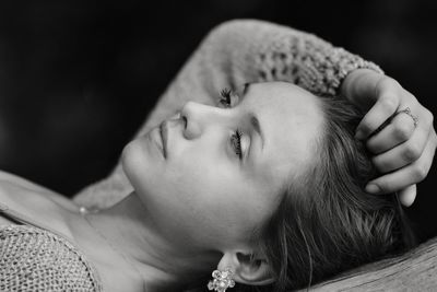 Young woman looking away while lying down against black background