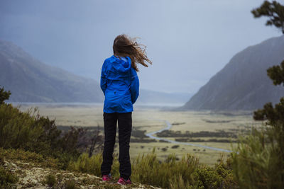 Rear view of woman standing on landscape against sky