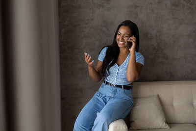 Young black woman working at home with smartphone on her couch in the living room. home office 