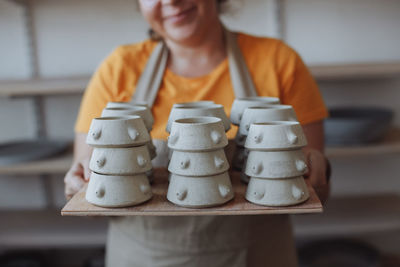 Woman potter holding mugs made by hand from clay