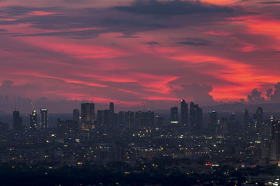 Illuminated buildings in city against sky during sunset