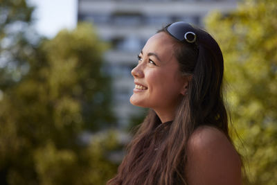 Smiling young woman sitting outdoor and looking away