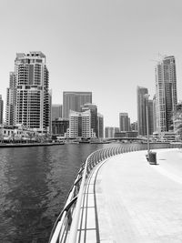 Modern buildings by river against clear sky