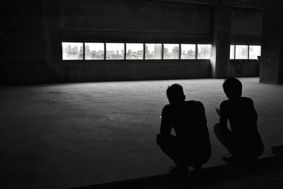 Rear view of silhouette people standing against window