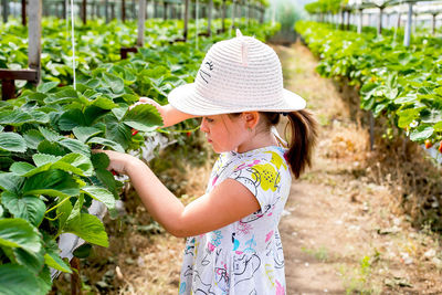 Cute girl doing gardening in greenhouse