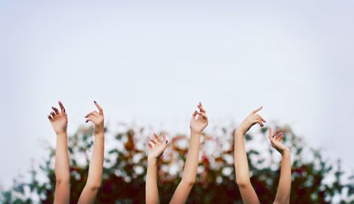 Raising hands against clear sky