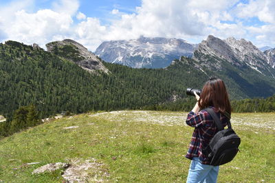 Rear view of woman standing on mountain against sky