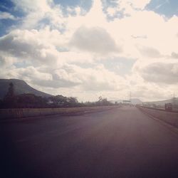 Empty road against cloudy sky