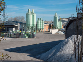 Outdoor space of a glass factory with vertical tanks and selected glass materials stacked together.