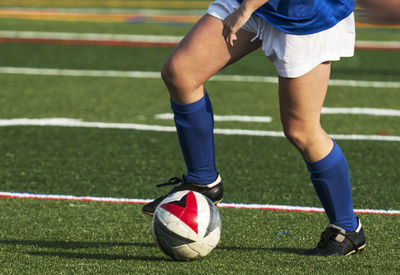 Low section of woman playing soccer on field