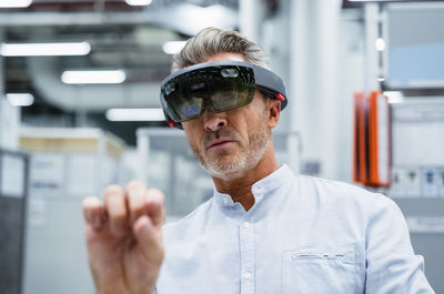 Businessman using augmented reality eyeglasses at factory