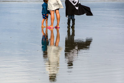 Low section of people standing at shore of beach