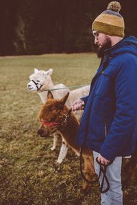 Man with animals standing on field