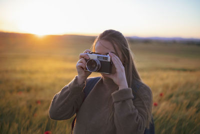 Girl taking a picture in the field with old camera