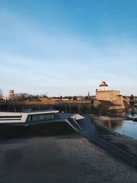 Buildings by river against sky in city