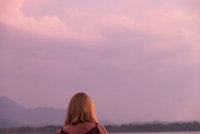 Rear view of woman looking at sky during sunset